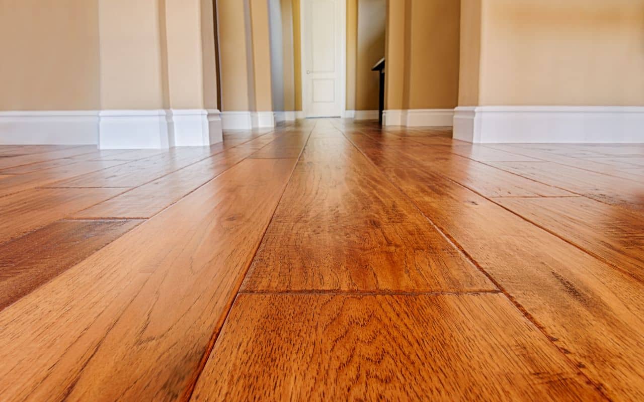 Eco-friendly hardwood flooring planks made from sustainably sourced white oak and maple with matte water-based finish displayed in a modern sustainable interior setting.